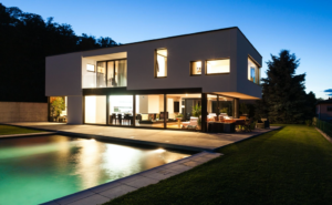 a home in night with lights on and pool in the backyard