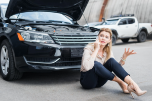 A lady calling car insurance with open-bonnet car behind her
