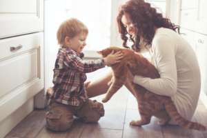 A kid and a woman playing with a cat