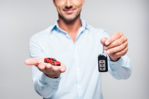 a man with a toy car in palm and holding car keys in other hand